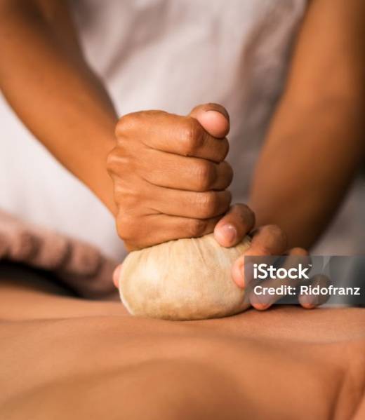 Closeup of masseuse hands holding cloth giving pinda massage to woman on spa table. Therapist hands giving ayurveda aroma pinda sweda massage to naked lady. Senior woman doing aromatic painkiller massage on back.